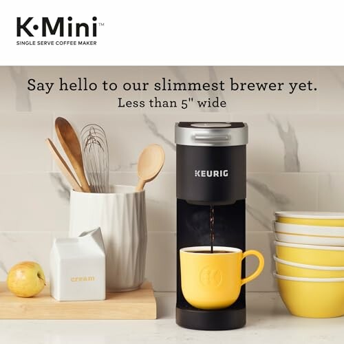 Keurig K-Mini coffee maker with a yellow mug, cream pitcher, and kitchen utensils